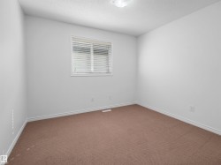 Carpeted room featuring a white-framed window with horizontal blinds, white walls, white baseboards, and a ceiling-mounted light fixture - 