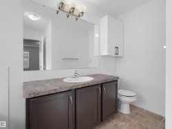 Bathroom featuring a vanity with a dark wood-finish base and a mottled countertop, an integrated sink, and a wall-mounted mirror - 
