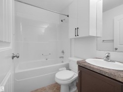 Bathroom featuring a white tub/shower combination, a dark wood-finish vanity with a built-in sink, and a mirrored medicine cabinet above - 