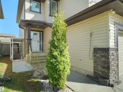 Two-story beige siding exterior with dark trim accents and stacked stone detailing - 
