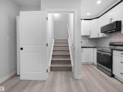 Modern kitchen featuring white cabinetry, subway tile backsplash, and stainless steel appliances - 