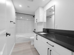 Contemporary bathroom featuring a white vanity with black hardware, a contrasting black countertop, and an integrated white sink - 