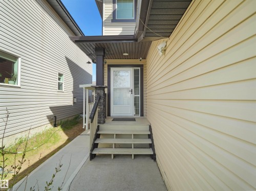 Front entrance featuring a covered porch with a stone-clad pillar, white storm door, and a three-step concrete staircase - 2017 32A Street, Edmonton, AB - Outdoor