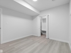 Spacious room featuring light wood-finish flooring, white walls, and bright baseboards - 