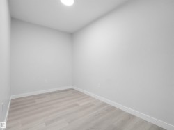 Interior room featuring light wood-finish flooring, white baseboards, and light gray walls - 