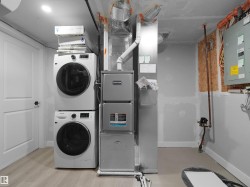 Utility room featuring a white paneled door with black hardware, light-toned wood-finish flooring, and a recessed ceiling light - 