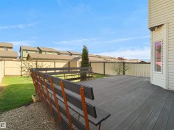 Private backyard featuring a spacious deck with a built-in railing, a manicured lawn, and a light-toned privacy fence - 