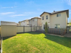 Expansive backyard featuring a manicured lawn, a detached storage shed, a multi-level deck, and a privacy fence - 