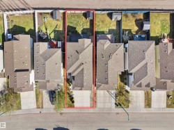 Aerial perspective showcasing a residential property with a multi-car driveway, a pitched roof, and a fenced backyard - 