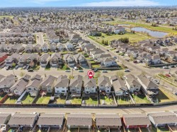 Aerial view of a residential neighborhood with detached homes, featuring a prominent pond and green space - 