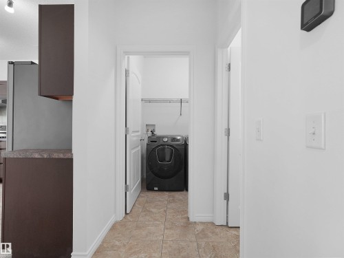 Dedicated laundry area featuring a front-load appliance, overhead shelving, and tiled flooring - 2017 32A Street, Edmonton, AB - Indoor Photo Showing Laundry Room