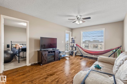 Spacious living area featuring wood-finish flooring, a ceiling fan with integrated lighting, and neutral wall tones - 412 5005 165 Avenue Nw, Edmonton, AB - Indoor Photo Showing Living Room