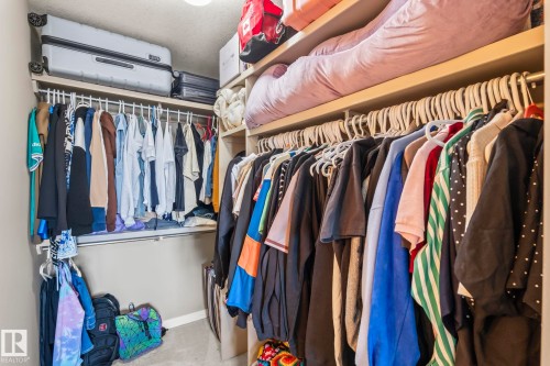 Built-in closet organization system featuring multiple hanging rods and shelving - 412 5005 165 Avenue Nw, Edmonton, AB - Indoor With Storage