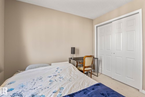 Neutral wall paint, white trim, and white bi-fold closet doors - 412 5005 165 Avenue Nw, Edmonton, AB - Indoor Photo Showing Bedroom