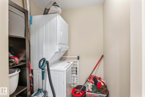 Dedicated laundry area featuring a stacked washer and dryer unit - 412 5005 165 Avenue Nw, Edmonton, AB - Indoor Photo Showing Laundry Room