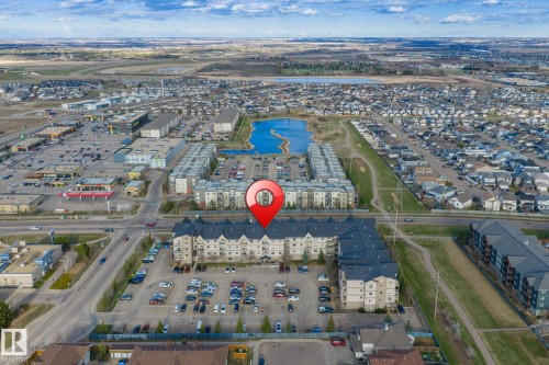 Multi-story building featuring light-colored siding and dark roofing, surrounded by a paved parking area - 412 5005 165 Avenue Nw, Edmonton, AB - Outdoor With View