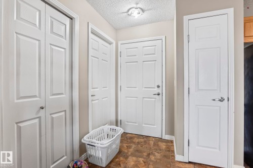 Entryway featuring paneled doors, textured ceiling, and a flush mount light fixture - 412 5005 165 Avenue Nw, Edmonton, AB - Indoor Photo Showing Other Room