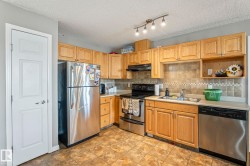 Kitchen featuring light wood cabinetry, a stainless steel refrigerator, and a stainless steel dishwasher - 