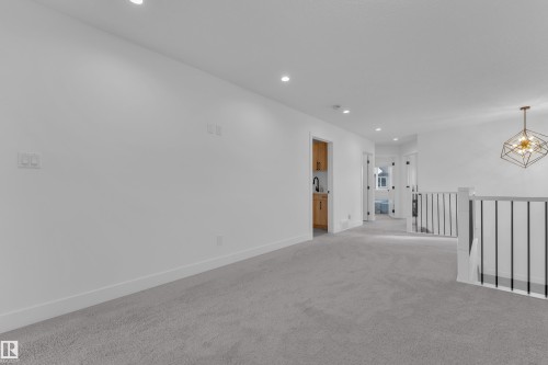 Carpeted hallway featuring a built-in wet bar with wood cabinetry and a black faucet, recessed lighting, and a modern geometric chandelier - 9 Hunter Place, Spruce Grove, AB - Indoor Photo Showing Other Room