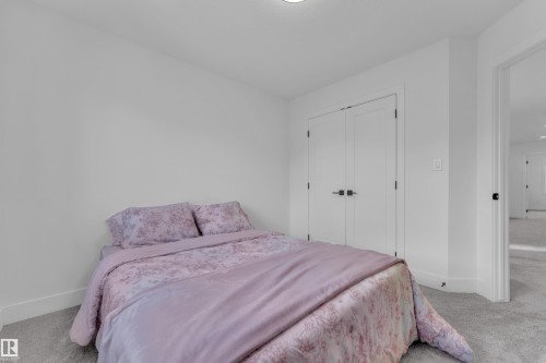 Carpeted room featuring a ceiling-mounted light fixture, white walls, white trim, and a white double door - 9 Hunter Place, Spruce Grove, AB - Indoor Photo Showing Bedroom