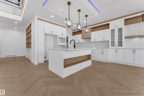 Modern kitchen featuring white cabinetry, a central island with integrated shelving, and herringbone wood-finish flooring - 12 Dalquist Bay, Leduc, AB - Indoor Photo Showing Kitchen With Upgraded Kitchen