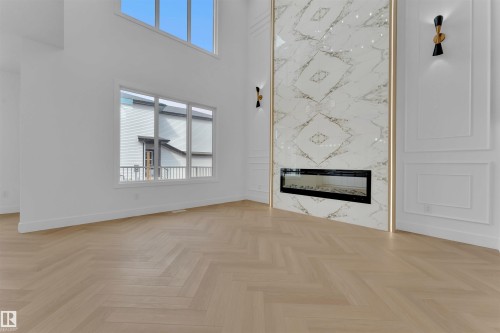 Spacious room featuring a herringbone wood-finish flooring, a two-story ceiling, and a large window arrangement - 12 Dalquist Bay, Leduc, AB - Indoor With Fireplace