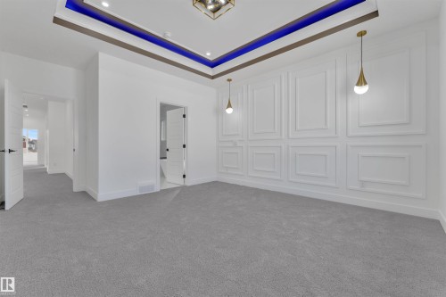 Spacious room featuring a decorative accent wall with panel molding, contemporary pendant lighting, and recessed ceiling lights - 12 Dalquist Bay, Leduc, AB - Indoor Photo Showing Other Room