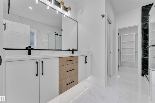Dual vanity with white cabinetry and wood-finish drawers, accented by matte black hardware and fixtures - 12 Dalquist Bay, Leduc, AB - Indoor