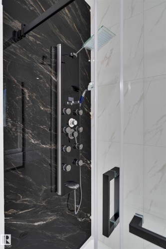Walk-in shower featuring black marbled walls, a multi-function shower panel with body jets, a rainfall showerhead, and a handheld spray - 12 Dalquist Bay, Leduc, AB - Indoor