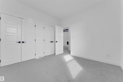 Light gray carpeted room featuring white walls, contemporary five-panel interior doors with matte black hardware, and crisp white baseboards - 12 Dalquist Bay, Leduc, AB - Indoor Photo Showing Other Room
