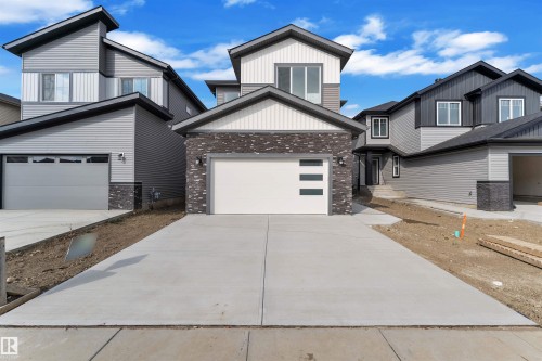 Contemporary home featuring a clean-lined exterior, a two-car garage with frosted glass panels, an asphalt shingle roof, and mixed siding with brick accents - 12 Dalquist Bay, Leduc, AB - Outdoor
