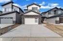 Contemporary home featuring a clean-lined exterior, a two-car garage with frosted glass panels, an asphalt shingle roof, and mixed siding with brick accents - 12 Dalquist Bay, Leduc, AB  - Outdoor 