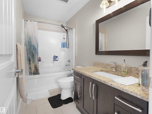 Bathroom featuring a dark wood-finish vanity with ample storage, a light-colored granite countertop, and an integrated rectangular sink - 5192 1B Ave Sw, Edmonton, AB - Indoor Photo Showing Bathroom
