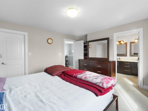 Spacious bedroom featuring light neutral wall tones, white trim, and a ceiling-mounted light fixture - 5192 1B Ave Sw, Edmonton, AB - Indoor Photo Showing Bedroom