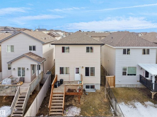 Rear exterior with light-toned siding, a multi-level wood deck, and a walk-out basement - 5192 1B Ave Sw, Edmonton, AB - Outdoor
