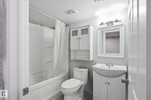 Bathroom featuring a white shower-tub combination, a vanity with a white cabinet and integrated sink, a wall-mounted medicine cabinet, and a framed mirror - 893 Ebbers Crescent Nw, Edmonton, AB - Indoor Photo Showing Bathroom
