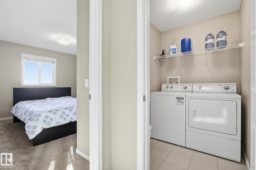 Dedicated laundry area featuring a washer and dryer, tiled flooring, and an overhead wire shelving unit - 893 Ebbers Crescent Nw, Edmonton, AB - Indoor Photo Showing Laundry Room
