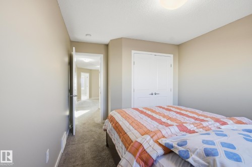 Neutral-toned walls and plush carpet flooring complement a white double-door closet - 893 Ebbers Crescent Nw, Edmonton, AB - Indoor Photo Showing Bedroom