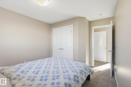 Neutral-toned interior room featuring carpeted flooring and a built-in closet with double white panel doors - 893 Ebbers Crescent Nw, Edmonton, AB - Indoor Photo Showing Bedroom