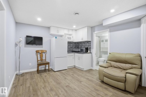 Compact kitchen area featuring white cabinetry, gray mosaic tile backsplash, and dark countertops - 893 Ebbers Crescent Nw, Edmonton, AB - Indoor