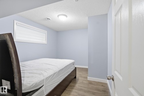 Bedroom featuring light blue walls, wood-finish flooring, and a horizontal window with blinds - 893 Ebbers Crescent Nw, Edmonton, AB - Indoor Photo Showing Bedroom