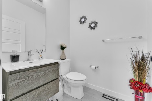 Modern bathroom featuring a floating wood-finish vanity with an integrated sink, polished chrome faucet, and a large wall-mounted mirror - 1645 Plum Circle Circle, Edmonton, AB - Indoor Photo Showing Bathroom