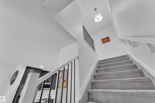 Carpeted staircase featuring white risers and a contemporary metal spindle railing with a white top rail - 1645 Plum Circle Circle, Edmonton, AB - Indoor Photo Showing Other Room