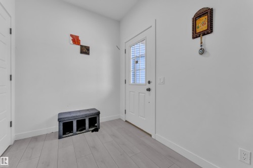 Entryway featuring a white paneled door with frosted glass insert, light wood-finish flooring, white baseboards, and neutral wall tones - 1645 Plum Circle Circle, Edmonton, AB - Indoor Photo Showing Other Room