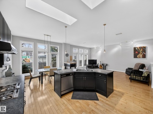Spacious open-concept living area featuring high ceilings, multiple skylights, and light wood-finish flooring - 569 Butterworth Way, Edmonton, AB - Indoor Photo Showing Kitchen