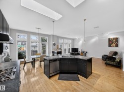 Spacious open-concept living area featuring high ceilings, multiple skylights, and light wood-finish flooring - 