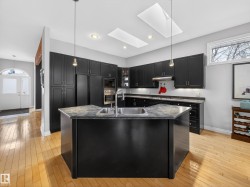 Gourmet kitchen with dark cabinetry, stainless steel appliances, and a central island featuring an undermount sink - 