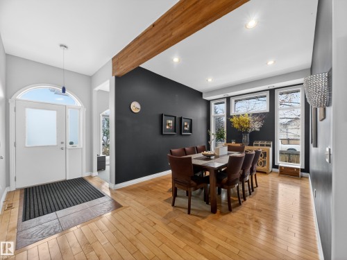 Entryway and dining area featuring wood-finish flooring, a prominent exposed wood beam, recessed lighting, and a white arched entryway with sidelights - 569 Butterworth Way, Edmonton, AB - Indoor Photo Showing Dining Room