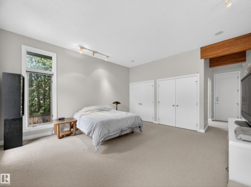 Spacious room featuring neutral carpeting, light gray walls, a large window, a track lighting fixture, and built-in closet doors - 569 Butterworth Way, Edmonton, AB - Indoor Photo Showing Bedroom