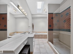Spacious bathroom featuring dual vanity with integrated sinks, a large soaking tub, and a separate glass-enclosed shower - 